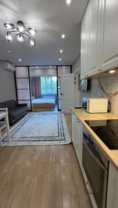 Una cocina con gabinetes blancos y una sala de estar. en Сердце Арбата, en Almaty
