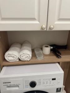 Un microondas con toallas en un estante encima de una lavadora. en Сердце Арбата, en Almaty