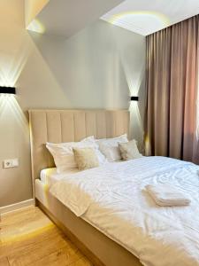 una habitación con una cama grande con sábanas y almohadas blancas en Сердце Арбата, en Almaty 5 fotos más