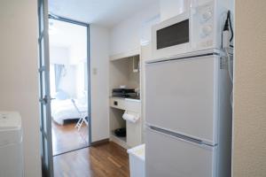 einen weißen Kühlschrank mit einer Mikrowelle darüber in der Unterkunft MinamiFukuokaHouse in Fukuoka