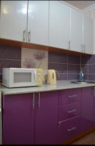 a kitchen with purple cabinets and a microwave on a counter at Назарбаева 19А уютная квартира в центре смарт тв wi-fi in Karagandy