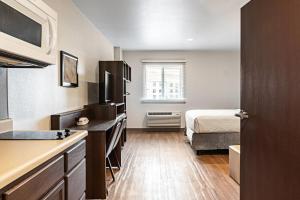 a small room with a bed and a kitchen at WoodSpring Suites Naples East in Naples