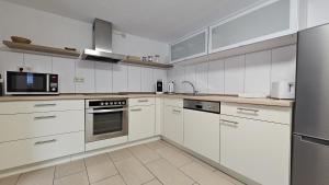 a kitchen with white cabinets and stainless steel appliances at 2 Zimmer Ferienwohnung mit Terrasse in Ehlscheid