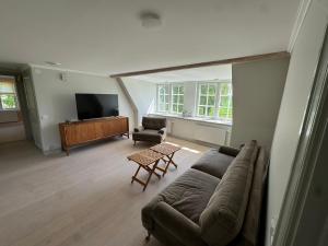 a living room with a couch and a tv at Miniatyr herrgård i Bro in Bro