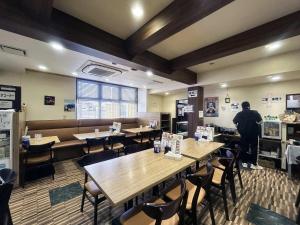 un homme debout dans un restaurant avec des tables et des chaises dans l'établissement Business Hotel Goi Onsen - Vacation STAY 78219v, à Ichihara