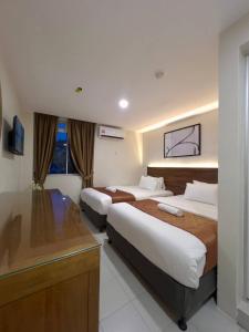 a hotel room with two beds and a desk at Hotel Istanaku , Ipoh, Perak in Ipoh
