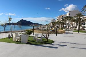 a park with white benches and a beach and buildings at Apartamento Avenida Altea 19 in Altea