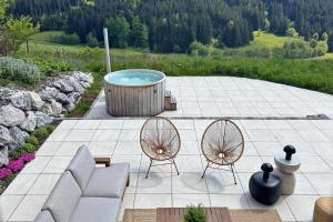 a patio with two chairs and a hot tub at Chalet Mädesüss in Weitnau