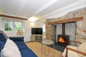 a living room with a blue couch and a fireplace at Sunrise Cottage in Bodmin