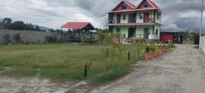 a house with a red roof on top of a field at Foothill homestay in Ranīchera