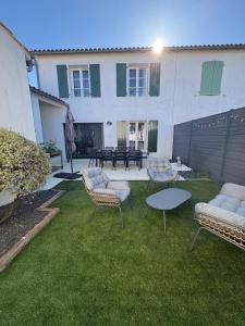un cortile con sedie e tavoli e un edificio di Charmante maison de Gros-Jonc a Le Bois-Plage-en-Ré Altre 14 foto