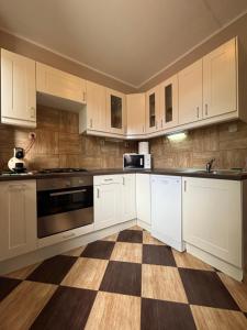 a kitchen with white cabinets and a checkered floor at Balian apartman in Siófok +19 photos