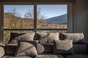 a couch with pillows in front of a large window at Mirador del Llac in Cellers