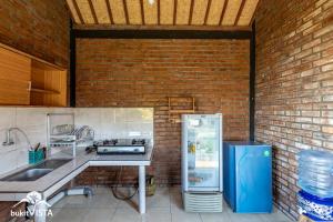 a kitchen with a refrigerator and a brick wall at Breeze Hidden Village by Bukit Vista in Uluwatu
