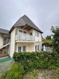 a white house with a balcony and bushes at Sarokház Rooms in Keszthely