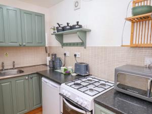eine Küche mit grünen Schränken und einem Herd oberen Backofen in der Unterkunft Wayside Farm Stable Cottage in Scarborough