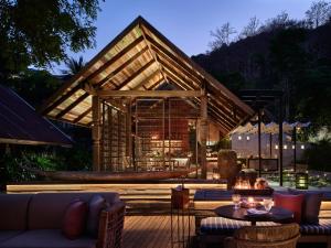 a patio with a large building with a table and chairs at Rosewood Phuket in Patong Beach