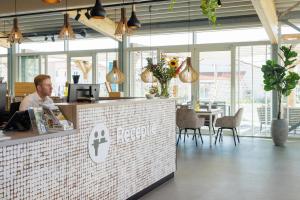 a man sitting at a counter in a restaurant at Duinresort Dunimar in Noordwijkerhout +17 photos