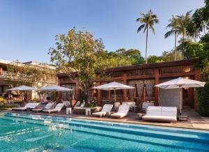 a swimming pool with lounge chairs and umbrellas at Rosewood Phuket in Patong Beach