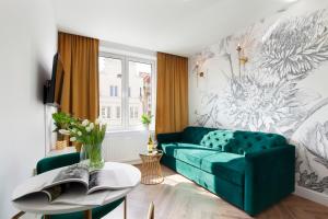 Una sala de estar con un sofá verde y una mesa. en Elite Apartments Ogarna Suites Old Town, en Gdansk