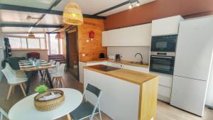 a kitchen with white cabinets and a table and a dining room at NEW Family Villa ideal para familias in Pineda de Mar