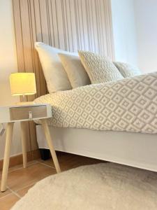 una cama con almohadas y una mesita de noche con lámpara en Les Nuits d'Embalens, en Castelnau-dʼEstrétefonds