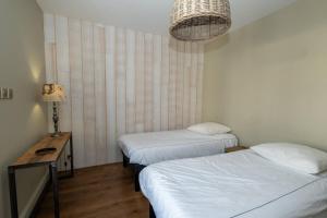 a room with two beds and a table and a lamp at MIA in La Noue