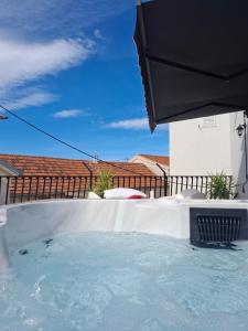 a hot tub in a backyard with an umbrella at CasaCalla in Okrug Donji