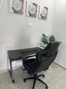 a black desk and a chair in front of a piano at Daria Homestay Seremban in Seremban +4 photos