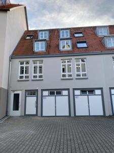 a white building with four garage doors and a roof at Ferienzimmer am Marktplatz in Bad Saulgau