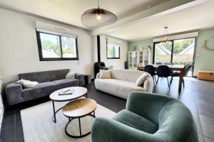 un salon avec deux canapés et une salle à manger dans l'établissement Belle maison contemporaine aux portes de Lorient, à Kervignac