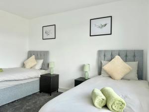two beds in a bedroom with white walls at Cosy 2 Bedroom home by Cheshunt Station Free Wifi and Parking in Cheshunt