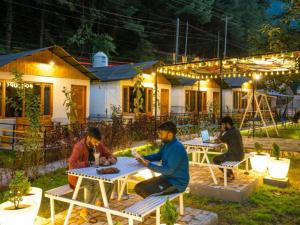 卡索尔The Hosteller Kasol, Riverside的一群坐在房子前面桌子的人