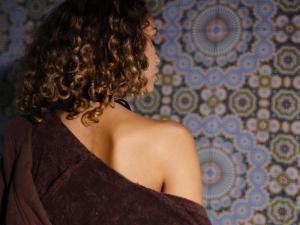 a woman with curly hair standing in front of a wall at 25hours Hotel Dubai One Central in Dubai