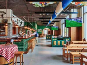 a person walking through a restaurant with tables and chairs at 25hours Hotel Dubai One Central in Dubai