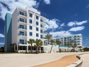 a white apartment building on the beach with palm trees at Treasure Island Beach Resort in St Pete Beach