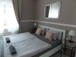 a bedroom with a white bed with pillows and a window at Éden Villa - Family Apartmanok in Balatonfüred