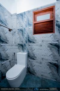 a bathroom with a toilet and a stone wall at BLUE WHALES HOTEL in Hikkaduwa +241 photos