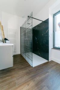 eine Glasdusche in einem weißen Raum mit Holzboden in der Unterkunft Maison spacieuse et jardin proche Soulages WisdhomeConciergerie in Rodez + 18 Fotos