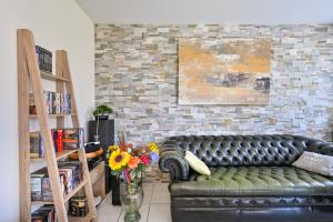 a living room with a black leather couch and flowers at L'Appart du Marché - A quelques min de la plage in Pornichet