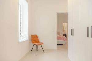 a chair in a white room with a bedroom at Serene Apartment in the Heart of Antwerp in Antwerp