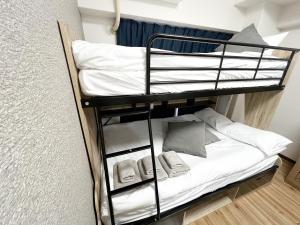 Etagenbett in einem Zimmer mit weißen Kissen in der Unterkunft サンシティ大濠公園 in Susakiuramachi