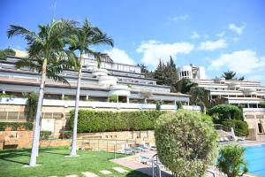a large white building with palm trees and a swimming pool at Monteverde Hotel in Beit Meri