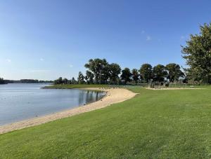 a sandy beach next to a body of water at Chalet De VeerWater in Recreatiepark De Veerstal in Lathum