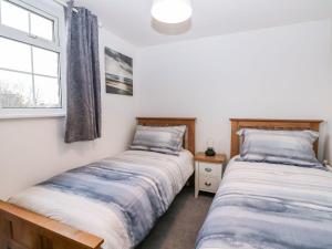 two twin beds in a room with a window at 2 Seaview Cottages in Pevensey