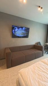 een woonkamer met een bank en een tv aan de muur bij Eleve Residences - Stone Studios in Sofia
