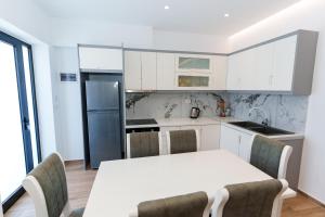 a kitchen with white cabinets and a table with chairs at Belmond Hotel in Ksamil