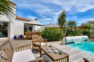 a patio with a table and chairs and a pool at Piscine chauffee 800 m de la plage villa pour 8 in Le Grand Vieil