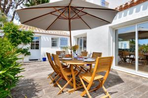 a wooden table and chairs with an umbrella on a patio at Piscine chauffee 800 m de la plage villa pour 8 in Le Grand Vieil