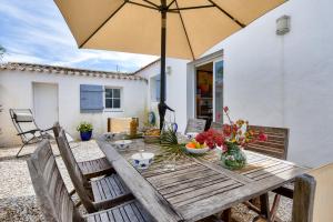 a wooden table with an umbrella on a patio at Piscine chauffee 800 m de la plage villa pour 8 in Le Grand Vieil